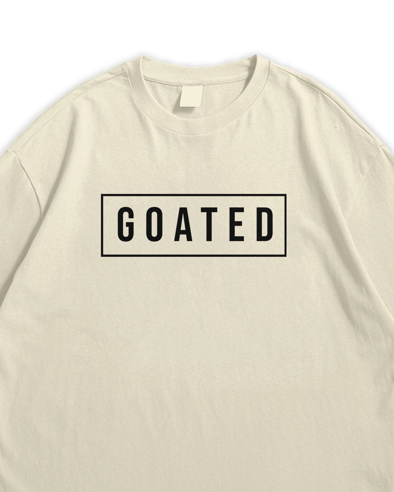 Beige t-shirt with 'GOATED' text on a white background